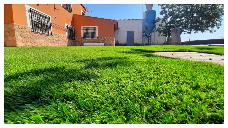 Césped artificial instalado en el jardín de una vivienda, con remates junto al pavimento