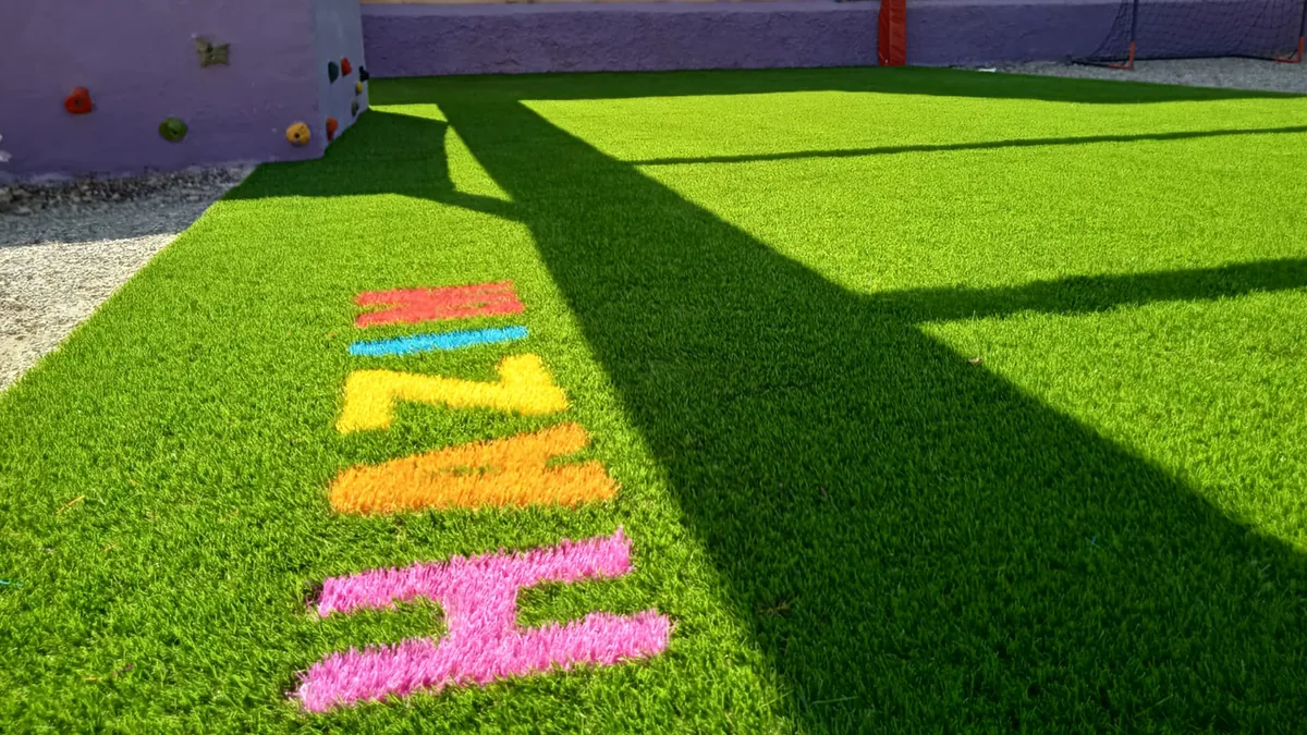 Composición con letras de distintos colores sobre césped artificial